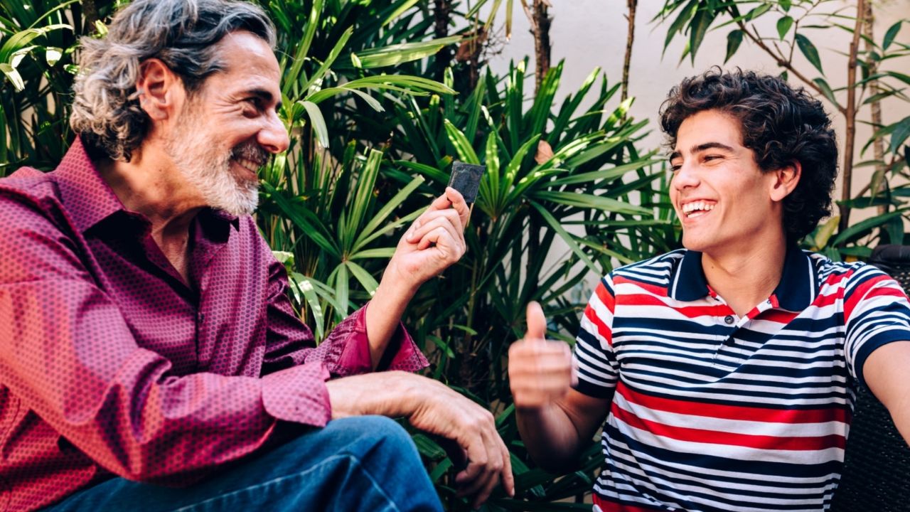 Pai dando a filho camisinha para que ele possa prevenir doenças sexualmente transmissíveis 