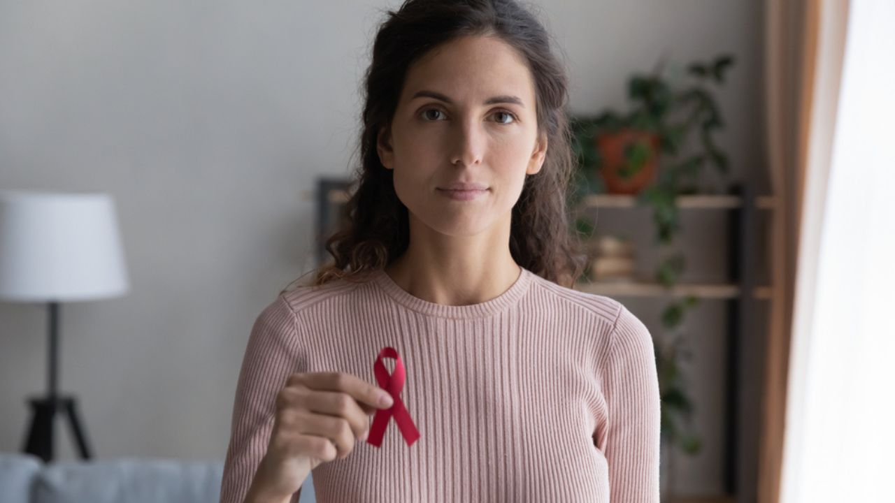 mulher apoiando a prevenção da Aids segurando a fita vermelha símbolo da campanha