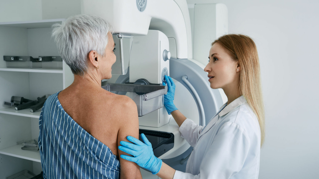 Uma médica realizando exame de mamografia em paciente com suspeita de um dos tipos de câncer: o câncer de mama.