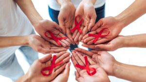 Mãos segurando fita vermelha, símbolo do Dezembro Vermelho