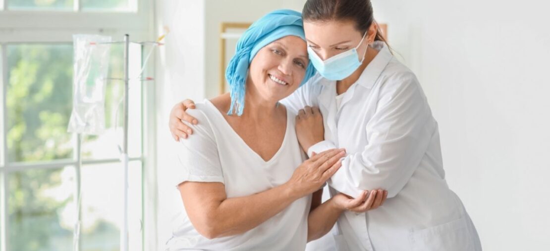 Uma médica e uma senhora portadora de câncer se abraçando.