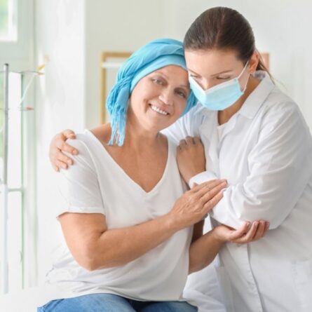 Uma médica e uma senhora portadora de câncer se abraçando.