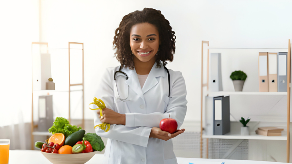 Uma jovem nutricionista em seu consultório, segurando uma fita métrica em uma mão e uma maça em outra.