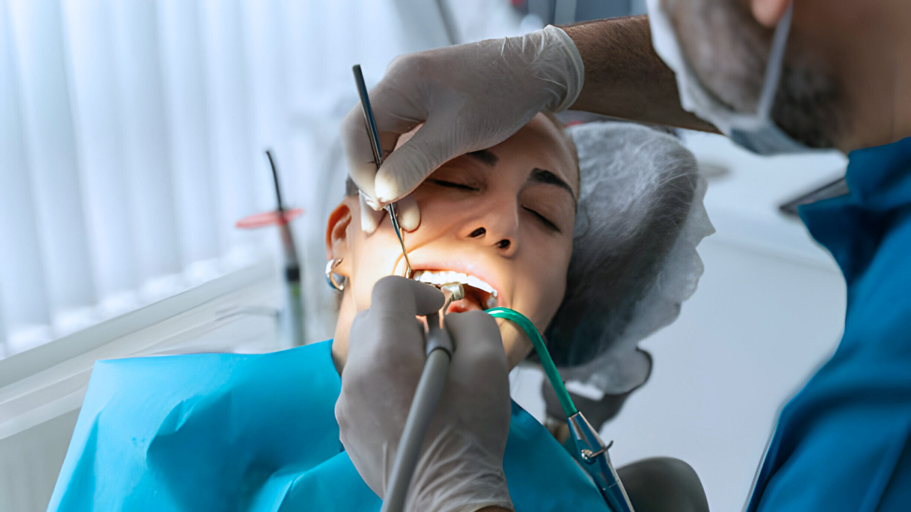 Um dentista, em seu consultório, realizando tratamento de periodontite na boca de uma paciente.