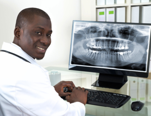 Médico odontologista avaliando resultado de raio X panorâmico odontológico.