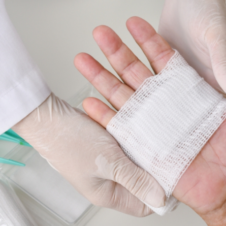 Um médico realizando curativo em ferida infeccionada de paciente.