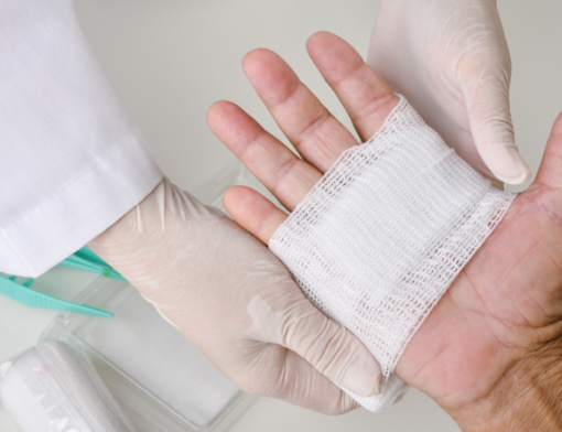 Um médico realizando curativo em ferida infeccionada de paciente.