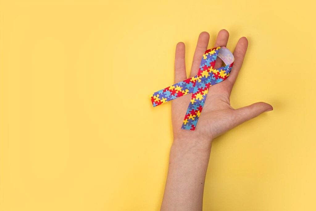 Mão segurando fita de quebra-cabeça de identificação autista