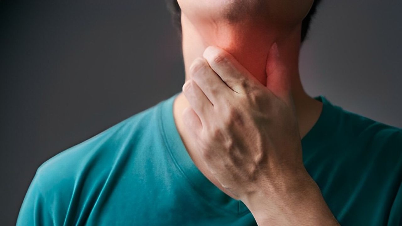 Zoom em homem com mão sobre garganta que está marcada de tom avermelhado para demonstrar problema na região
