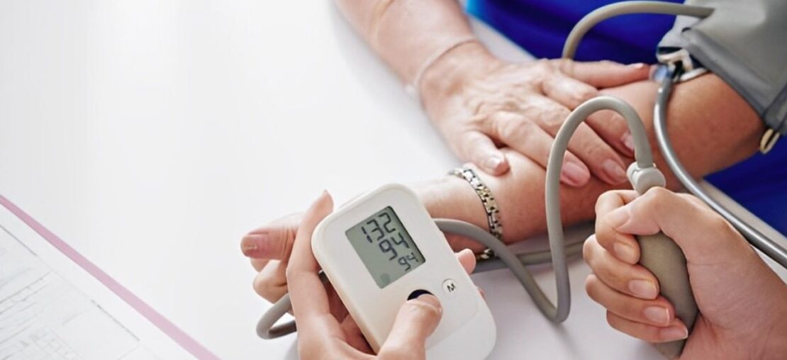 Zoom nas mãos de médico realizando a medição de pressão em paciente