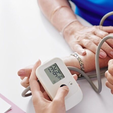 Zoom nas mãos de médico realizando a medição de pressão em paciente