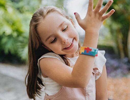 Menina criança olhando para sua pulseira de identificação de autismo