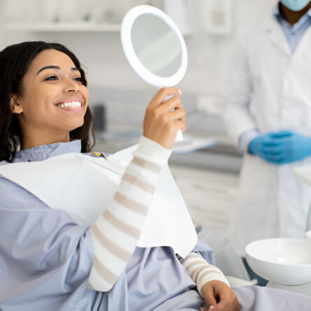 Mulher observando seu sorriso após fazer clareamento dental valor