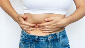 Zoom de mulher apertando seu lado esquerdo abaixo da costela por conta de dor