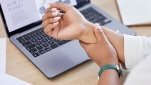 Mulher sentindo dores no pulso em razão de uma lesão por esforço repetitivo