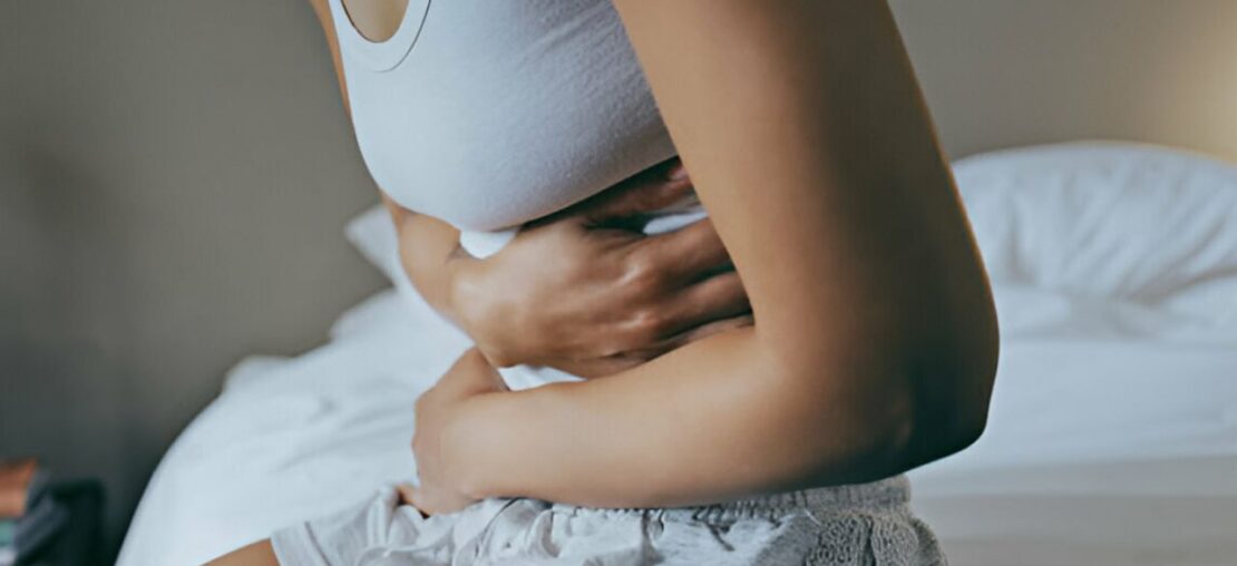 Zoom em mulher apertando a barriga por conta de mal estar no estômago