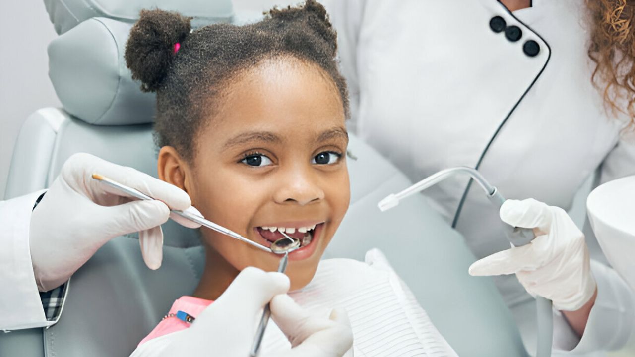 Zoom em rosto de criança menina recebendo atendimento de odontopediatra em maca de consultório