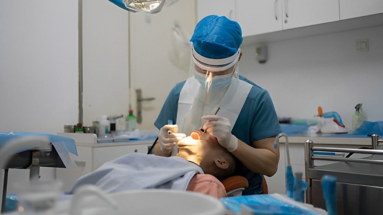 Dentista realizando preparação para tratamento da pericoronarite em consultório odontológico